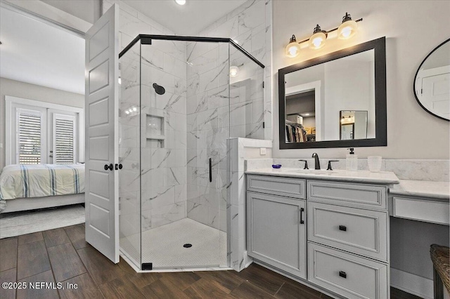 full bathroom featuring a marble finish shower, vanity, ensuite bath, and wood finish floors