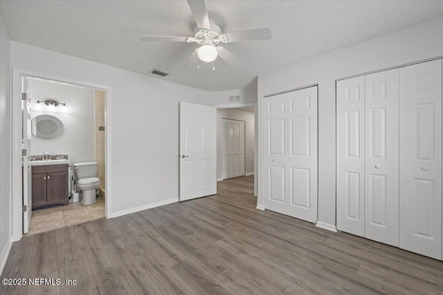 unfurnished bedroom featuring wood finished floors, visible vents, and a textured ceiling