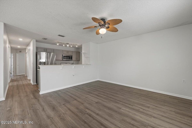 unfurnished living room with visible vents, baseboards, dark wood-style flooring, and a textured ceiling