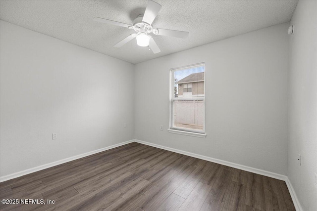 spare room with a textured ceiling, baseboards, dark wood-type flooring, and ceiling fan