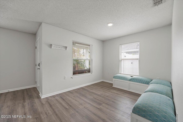 sitting room with baseboards, a textured ceiling, and wood finished floors