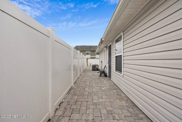 view of side of property with cooling unit, a patio, and a fenced backyard