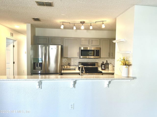 kitchen with visible vents, backsplash, appliances with stainless steel finishes, and gray cabinetry