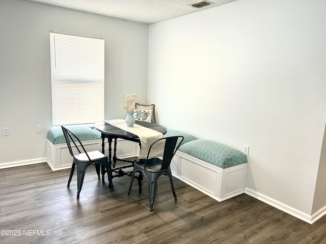 dining room featuring dark wood finished floors, baseboards, visible vents, and a textured ceiling