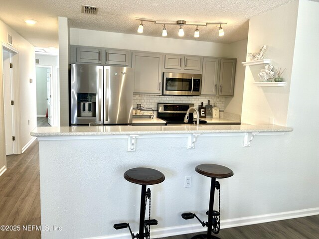 kitchen featuring visible vents, backsplash, dark wood finished floors, gray cabinets, and stainless steel appliances