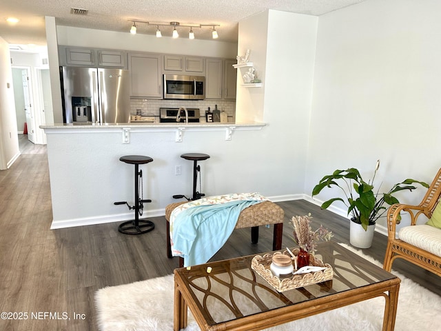 living area featuring dark wood finished floors, baseboards, visible vents, and a textured ceiling