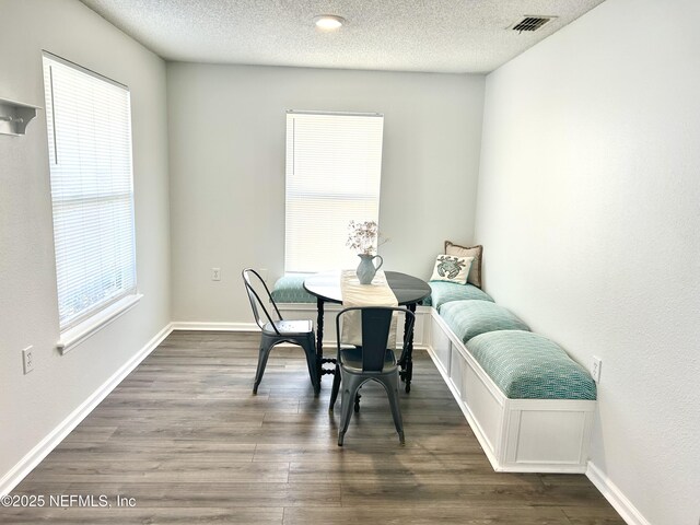 dining room featuring dark wood finished floors, baseboards, visible vents, and a textured ceiling