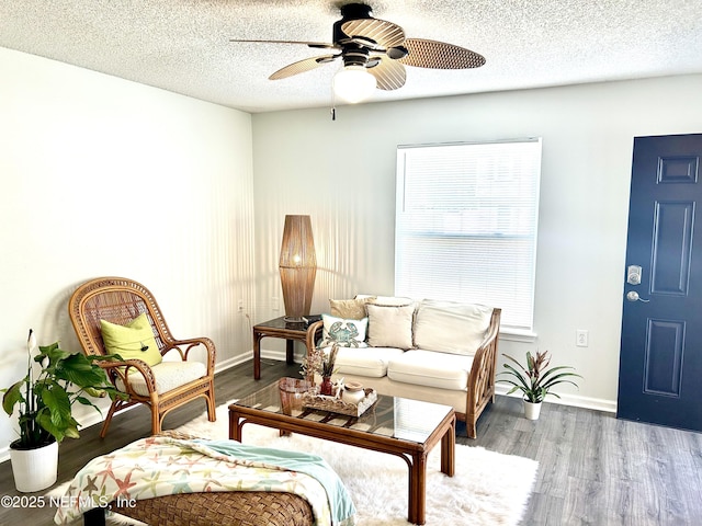 living area with baseboards, a textured ceiling, wood finished floors, and a ceiling fan