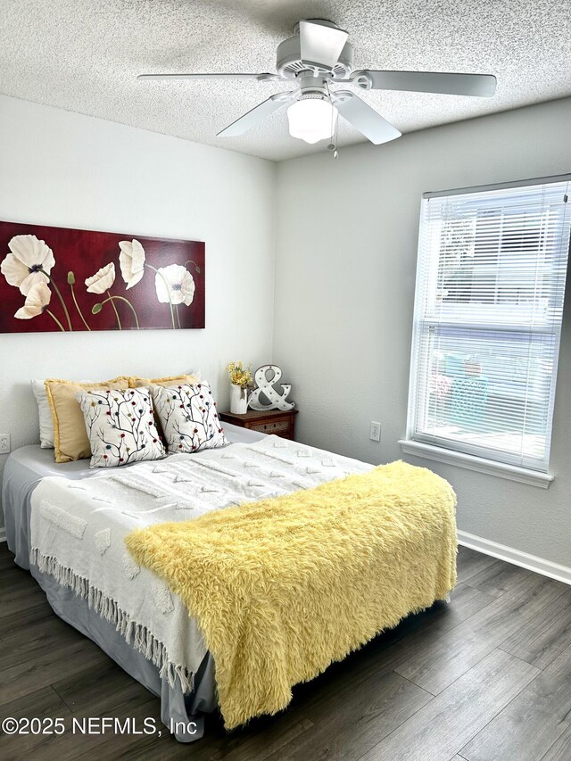 bedroom featuring multiple windows, a textured ceiling, and wood finished floors