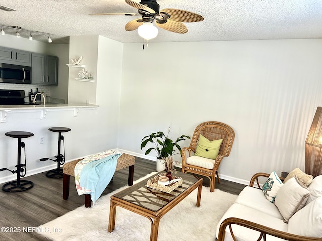 living area featuring visible vents, a textured ceiling, dark wood-type flooring, and baseboards