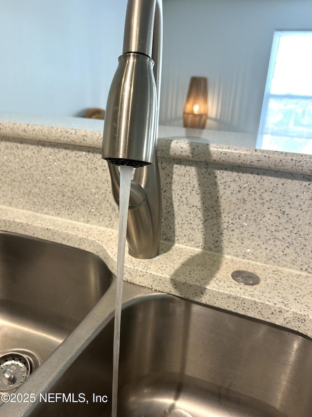 interior details featuring light stone counters and a sink