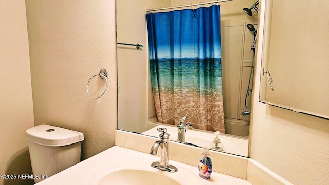 full bathroom with toilet, vanity, and a textured wall