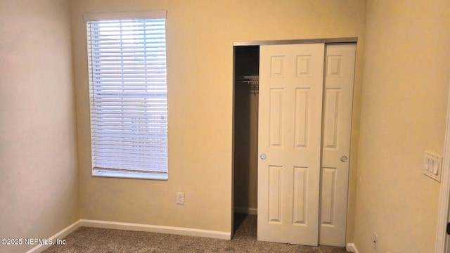 unfurnished bedroom with carpet flooring, baseboards, and a closet