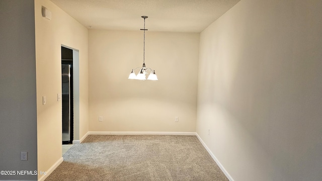 spare room with a notable chandelier, baseboards, and carpet