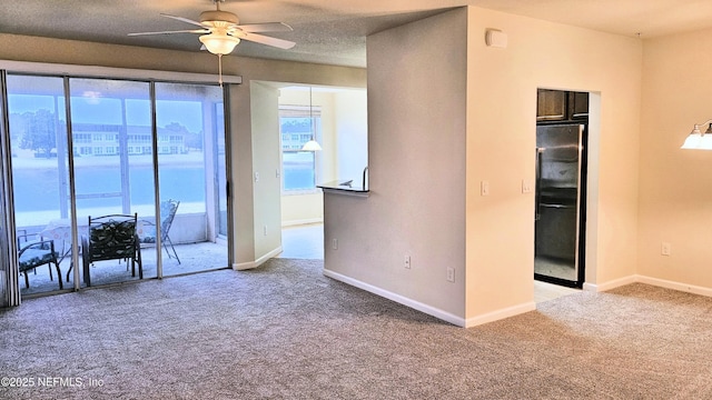 carpeted spare room featuring baseboards and a ceiling fan