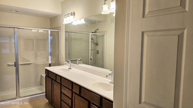 bathroom featuring tile patterned flooring, a shower stall, double vanity, and a sink