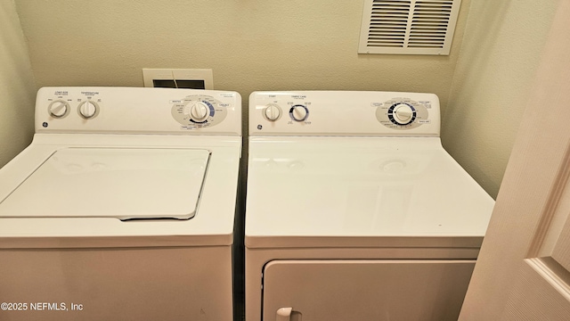 laundry room with washer and dryer, laundry area, a textured wall, and visible vents