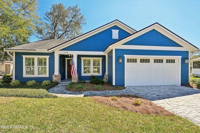 view of front facade with decorative driveway, a front lawn, and an attached garage