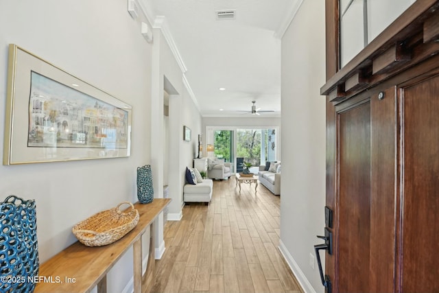 hallway featuring baseboards, visible vents, light wood finished floors, recessed lighting, and crown molding