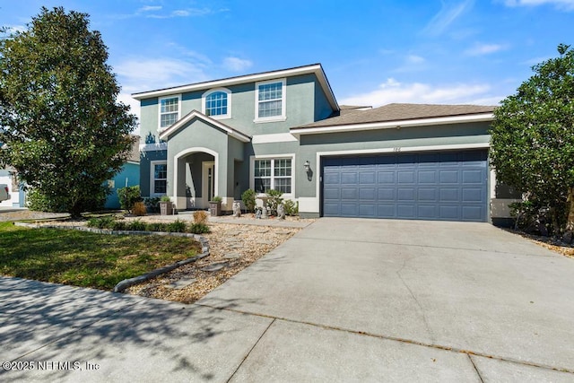 traditional-style house featuring a garage, driveway, and stucco siding