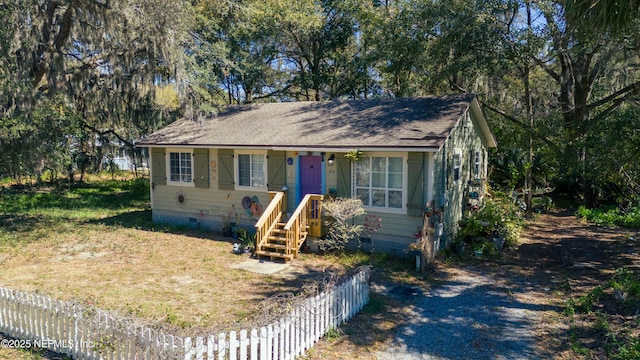 view of front facade featuring crawl space, a shingled roof, and fence