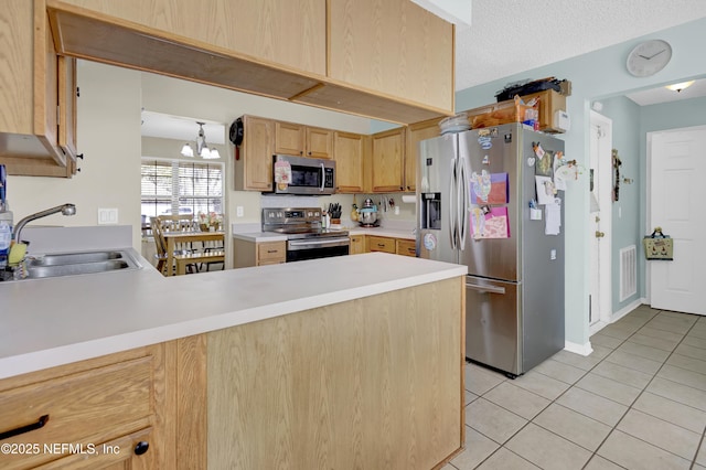 kitchen featuring light tile patterned flooring, stainless steel appliances, a peninsula, a sink, and light countertops