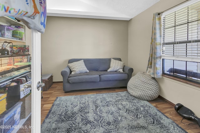 living area with a textured ceiling, baseboards, and wood finished floors