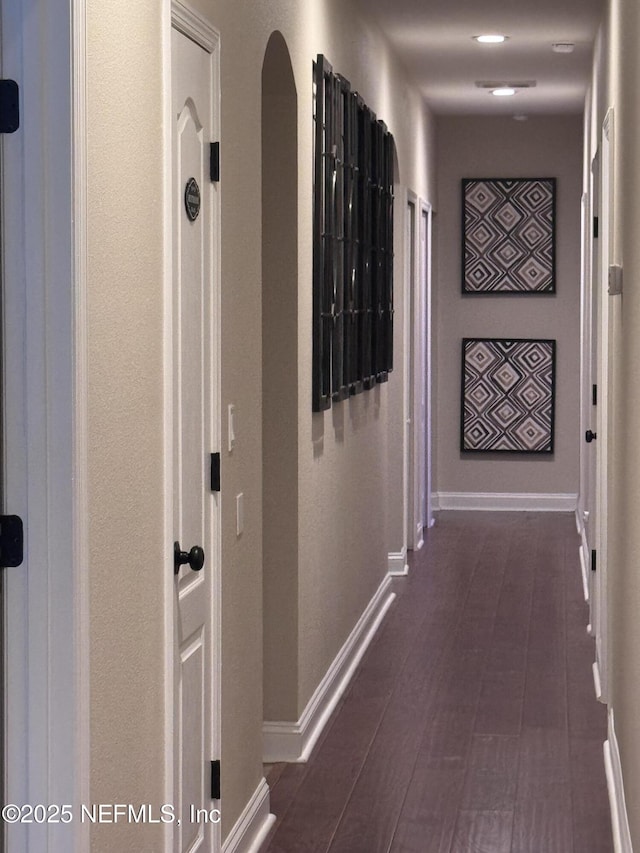 corridor featuring dark wood-style floors and baseboards