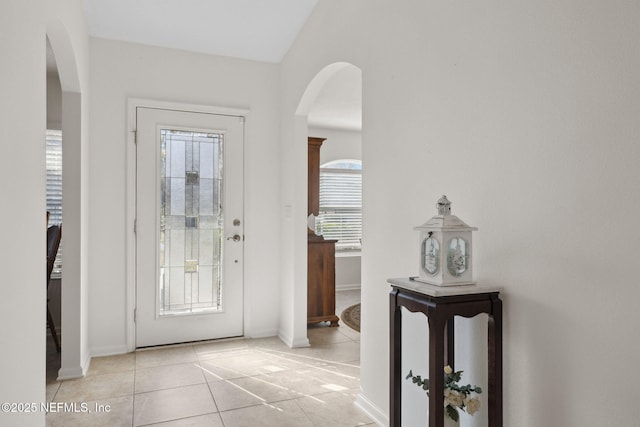 foyer entrance with arched walkways and light tile patterned flooring