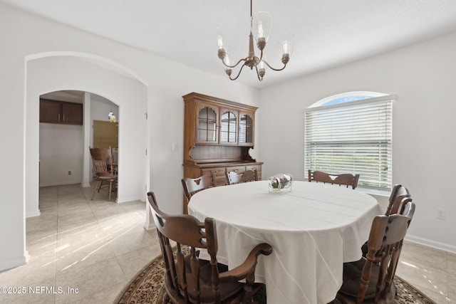 dining room featuring arched walkways, a chandelier, and baseboards