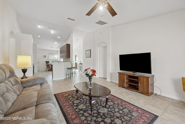 living room with arched walkways, light tile patterned flooring, and visible vents