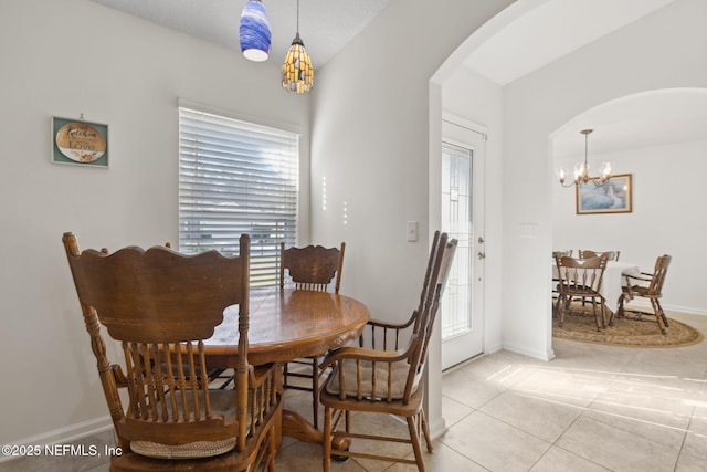 dining area featuring baseboards, arched walkways, a notable chandelier, and light tile patterned flooring