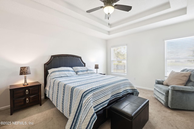 bedroom featuring a tray ceiling, light colored carpet, and baseboards