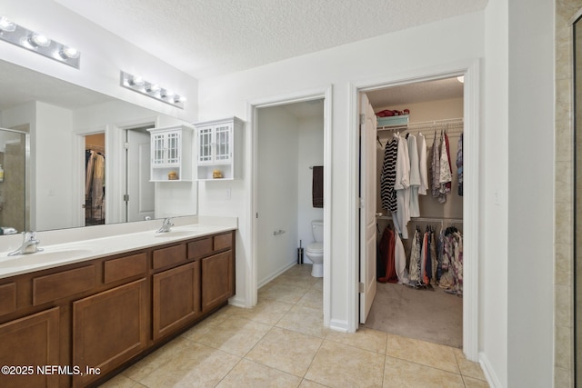 bathroom featuring a stall shower, a sink, a textured ceiling, and toilet