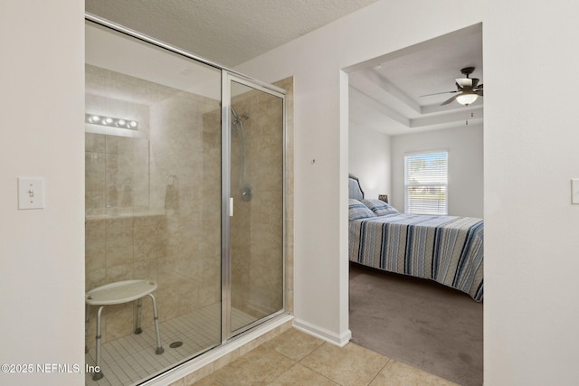 ensuite bathroom with ceiling fan, a shower stall, ensuite bath, a textured ceiling, and tile patterned flooring