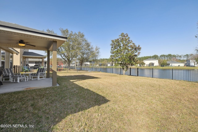 view of yard with ceiling fan, a fenced backyard, a water view, and a patio