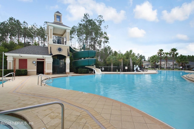 pool featuring a water slide, a patio area, and fence