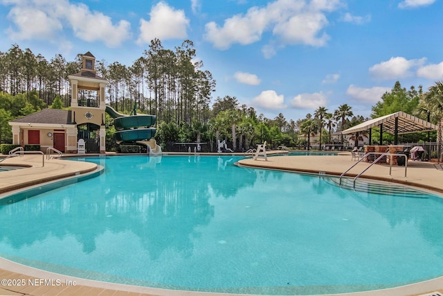 community pool with a water slide and a patio