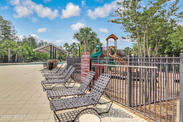 view of patio / terrace with playground community, fence, and a community pool