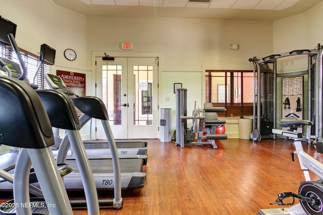 gym with french doors, wood finished floors, a wealth of natural light, and crown molding