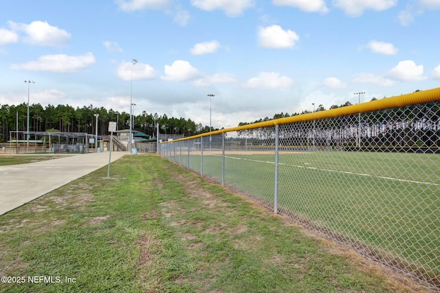 view of sport court with fence and a lawn