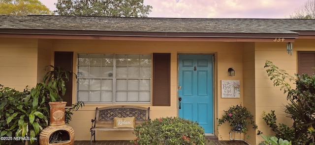 view of exterior entry with roof with shingles