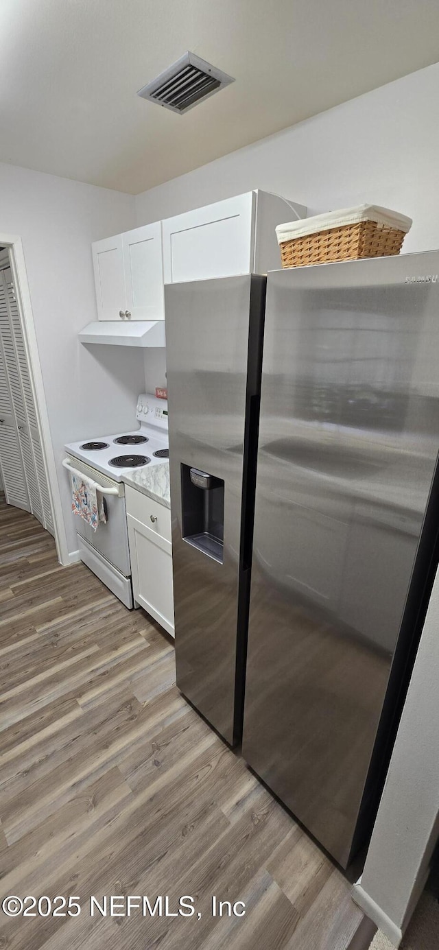 kitchen with white range with electric stovetop, light wood finished floors, visible vents, freestanding refrigerator, and white cabinetry