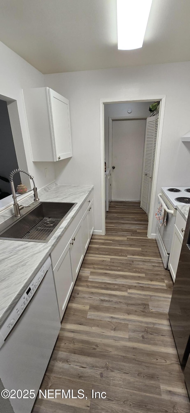 kitchen featuring white appliances, white cabinets, wood finished floors, light countertops, and a sink