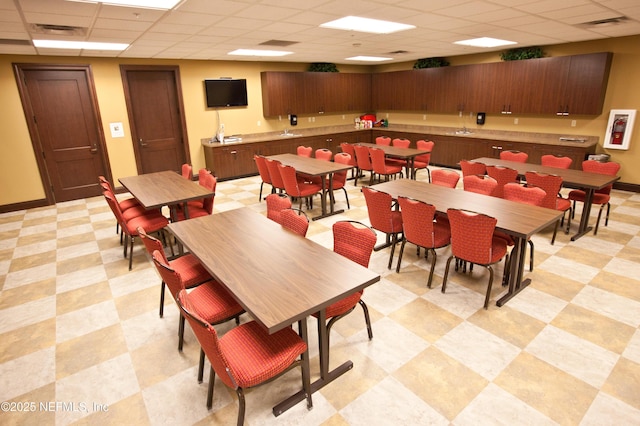 dining room featuring visible vents, light floors, baseboards, and a drop ceiling