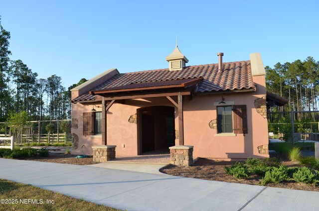 exterior space with a tiled roof, fence, and stucco siding