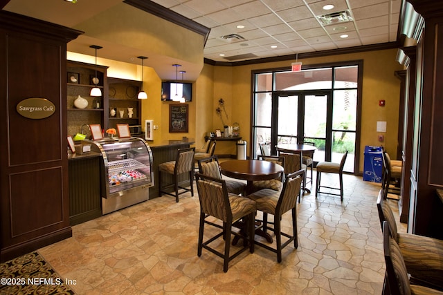 dining space featuring stone finish flooring, visible vents, crown molding, and french doors