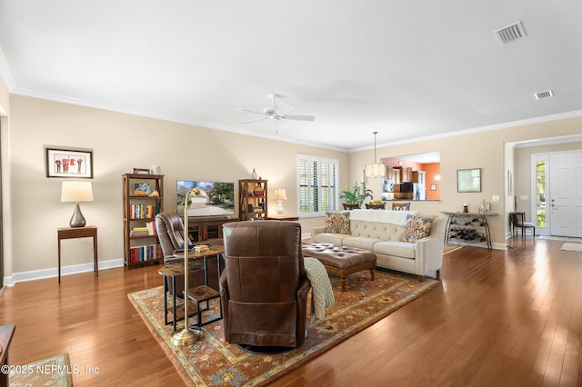 living area with visible vents, hardwood / wood-style floors, and crown molding