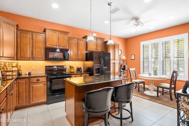 kitchen with backsplash, a center island, light tile patterned floors, brown cabinets, and black appliances