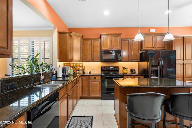 kitchen with tasteful backsplash, a breakfast bar, light tile patterned floors, black appliances, and a sink